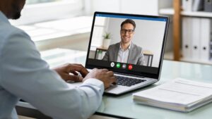 Person conducting a remote online commissioning session with a laptop and documents